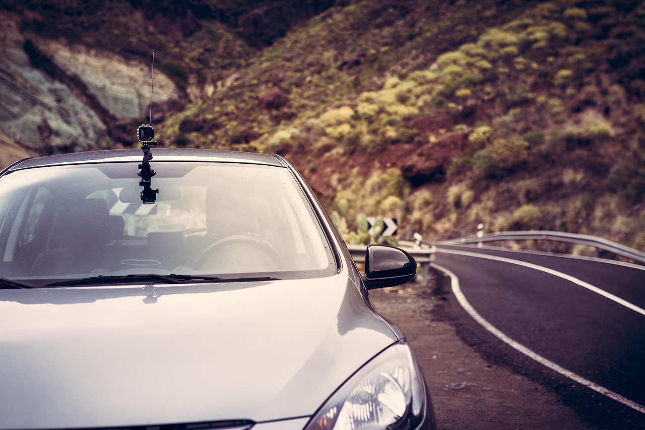 SUV driving down a scenic mountain highway with a roof cargo carrier attached.
