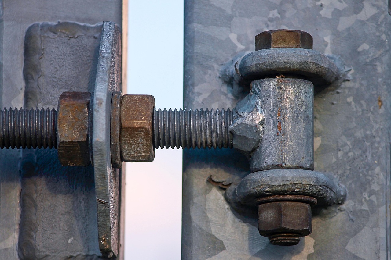 Close-up of a metal hinge mechanism on an automotive accessory being inspected with a tool.