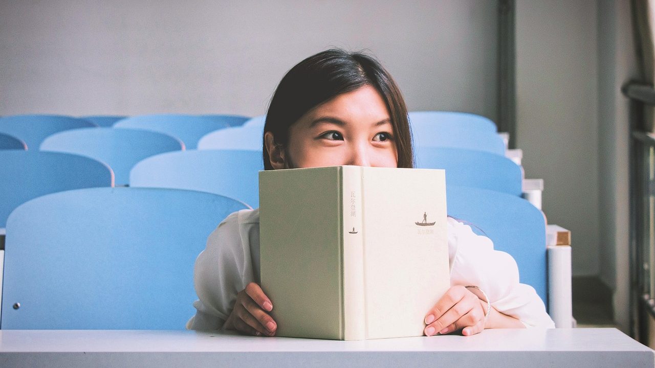 A person focused on reading articles at a clean wooden desk with a laptop.