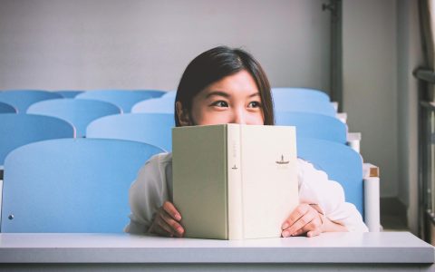 A person focused on reading articles at a clean wooden desk with a laptop.