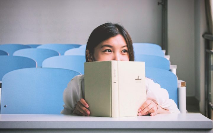 A person focused on reading articles at a clean wooden desk with a laptop.
