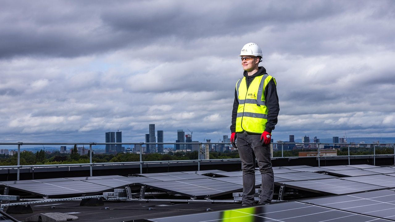 A technician inspecting solar panel mounting brackets on a shingle roof