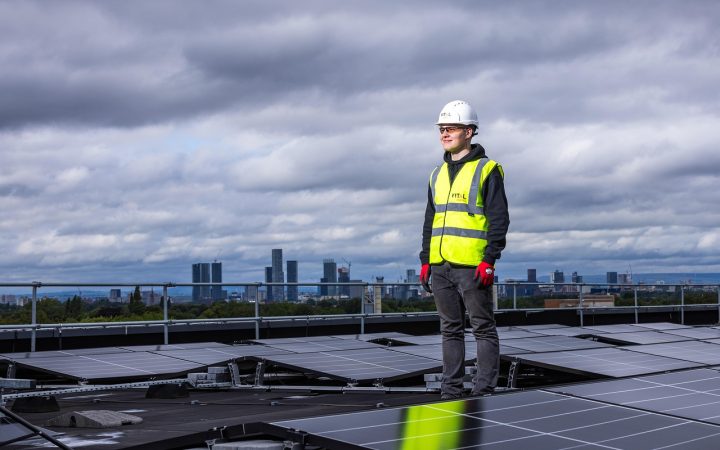 A technician inspecting solar panel mounting brackets on a shingle roof