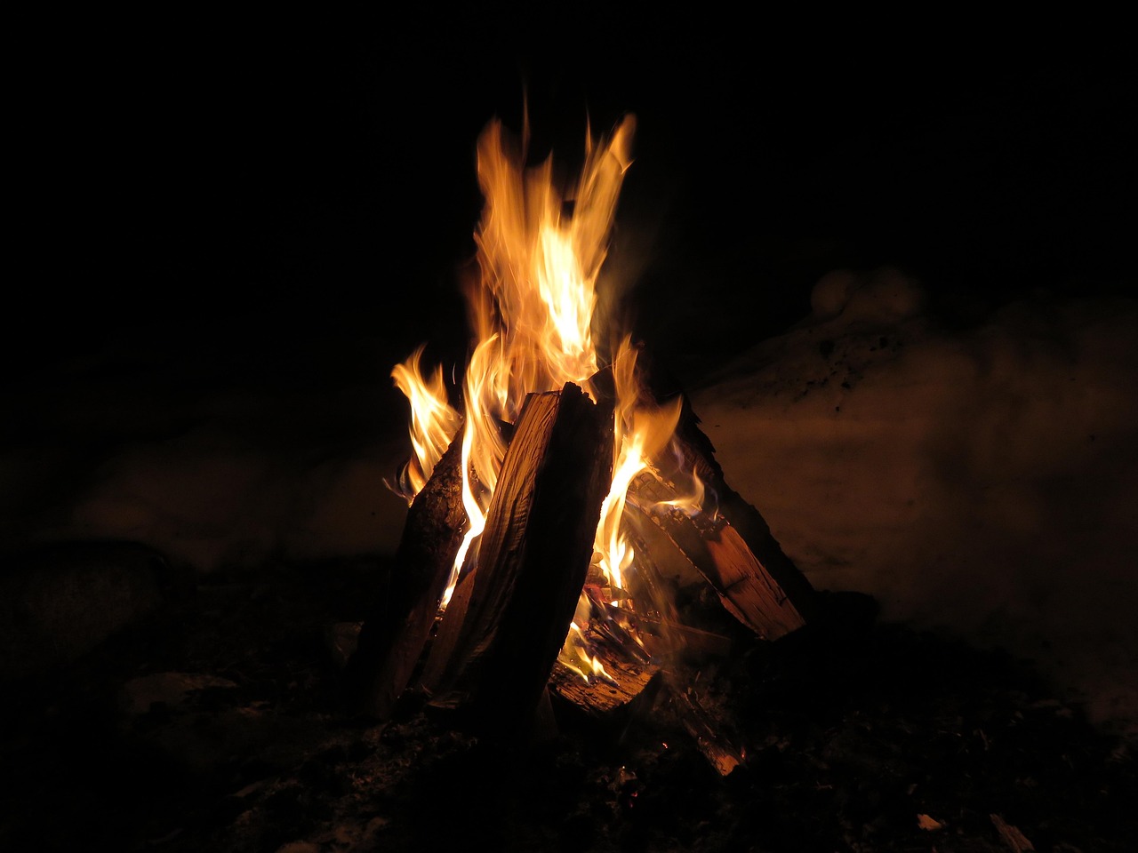 A warm campfire burning brightly in a stone fire ring at a state park campground.