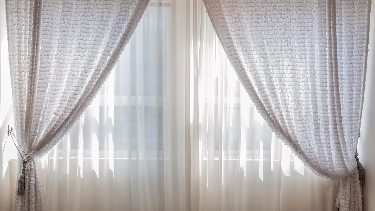 Heavy wool thermal curtain hanging over a wooden entryway interior in a cold home.