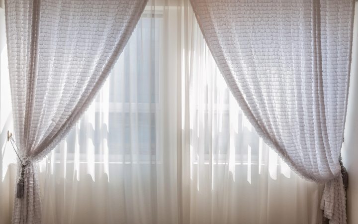 Heavy wool thermal curtain hanging over a wooden entryway interior in a cold home.