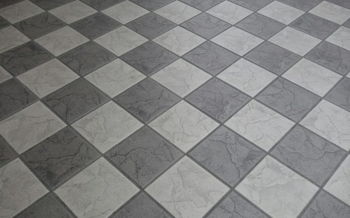 Contractor using a tape measure on a kitchen floor before tile installation
