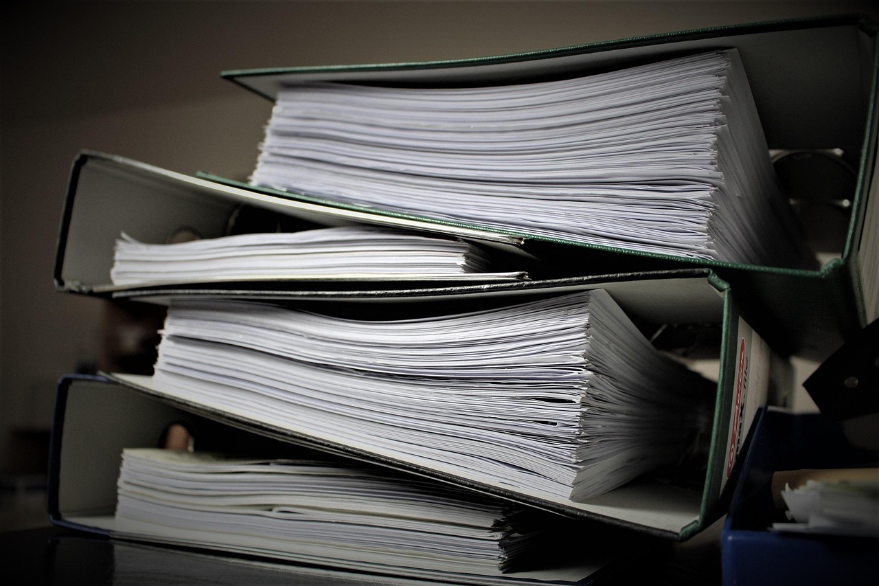 Person sorting through title documents, proof of insurance, and registration forms on a table.