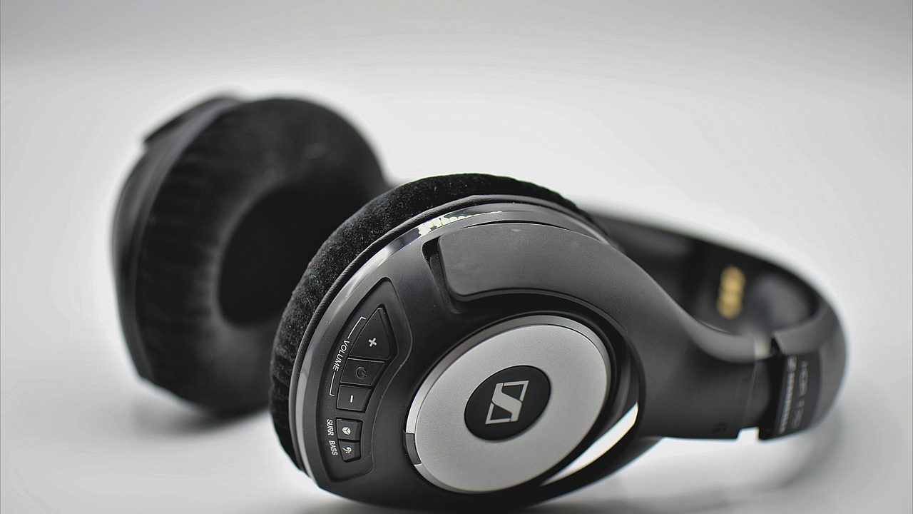 Close-up of a clean wooden desk with professional headphones hanging securely underneath.