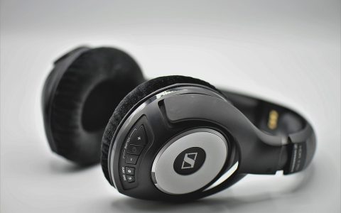 Close-up of a clean wooden desk with professional headphones hanging securely underneath.