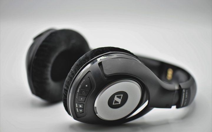 Close-up of a clean wooden desk with professional headphones hanging securely underneath.