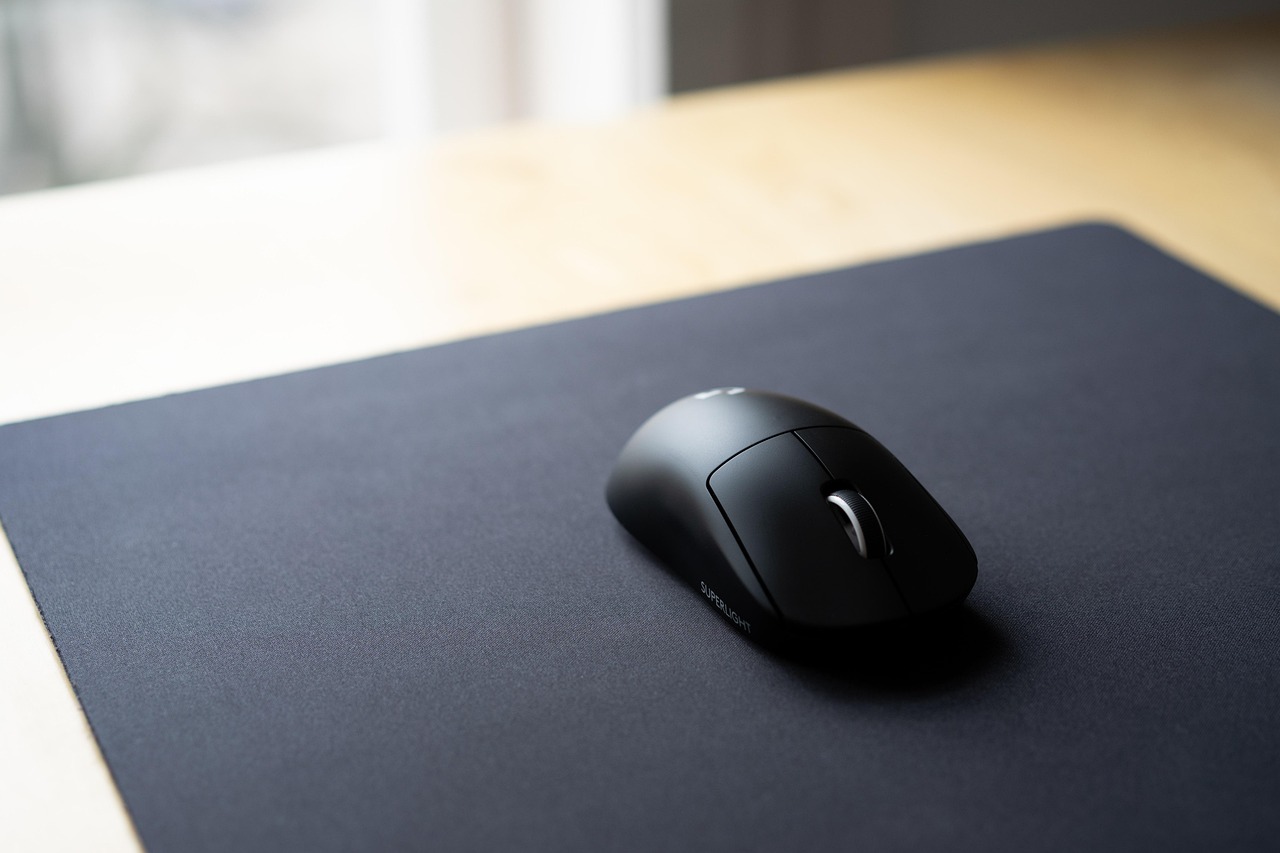 Wireless computer mouse and mechanical keyboard on a wooden desk.