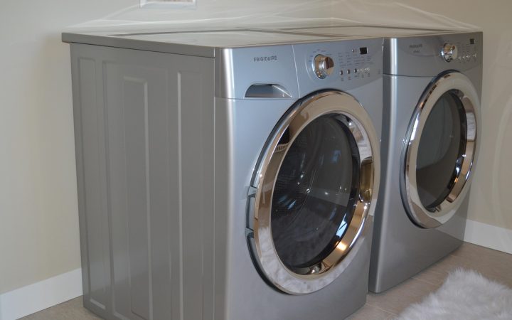 Front-load washer and dryer set installed on matching metal storage pedestals in a modern laundry room.