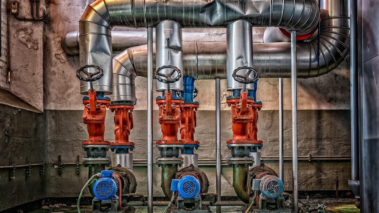 Plumber inspecting a residential water pressure reducing valve on a main supply line.