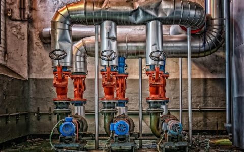 Plumber inspecting a residential water pressure reducing valve on a main supply line.