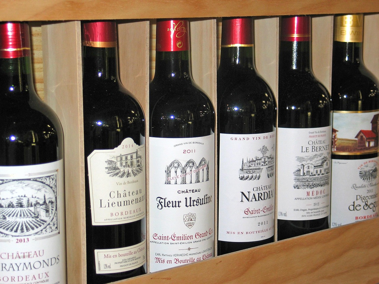 Close up of wine bottles stored horizontally on wooden shelves inside a chiller