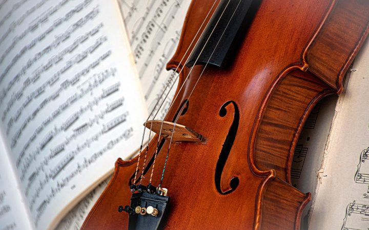 High school student playing violin in a youth orchestra rehearsal