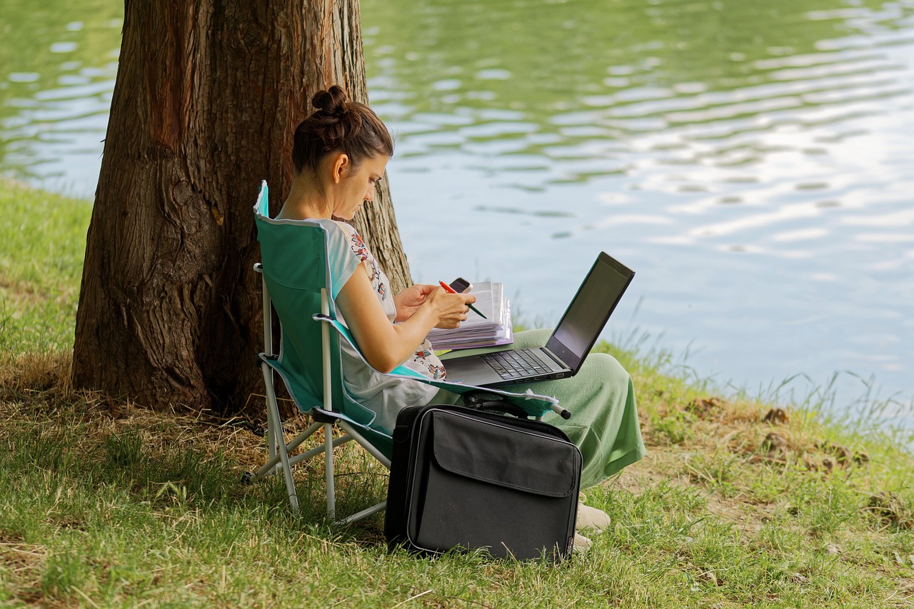 Remote worker focused on a laptop behind a dark grey fabric acoustic desktop divider.