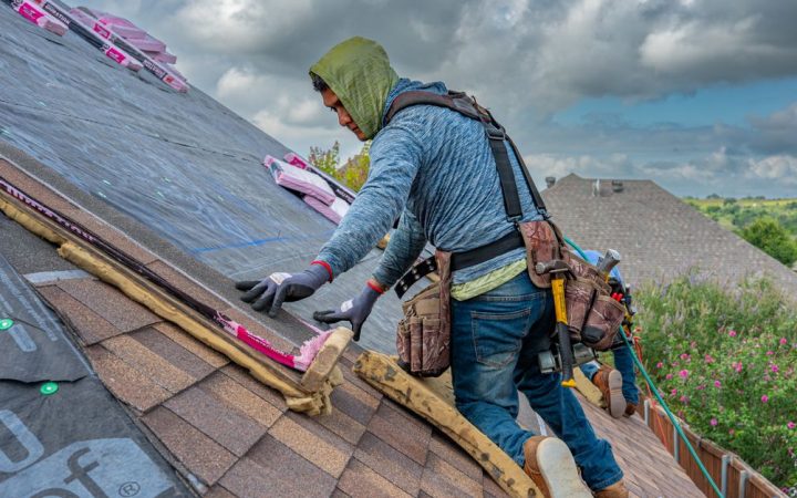 Worker blowing loose fill insulation into a residential attic space