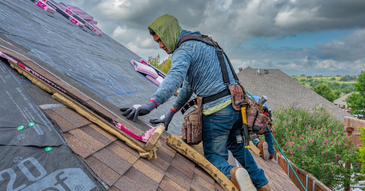 Worker blowing loose fill insulation into a residential attic space