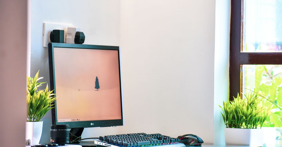 Clean home office desk setup positioned near a bright window with proper lighting management