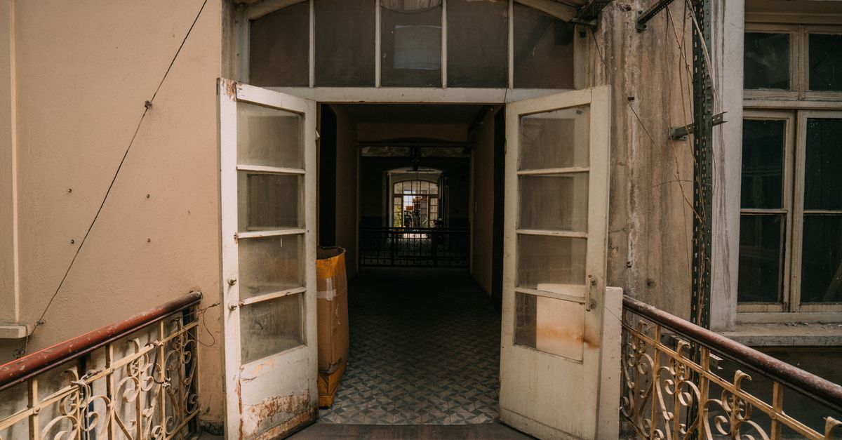 An apartment building hallway featuring unit doors and trash bins.