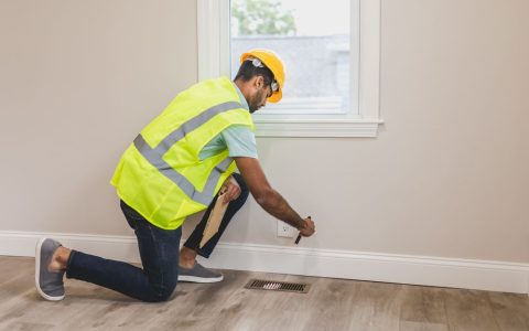 A homeowner inspecting insulation and framing in an unfinished attic space.