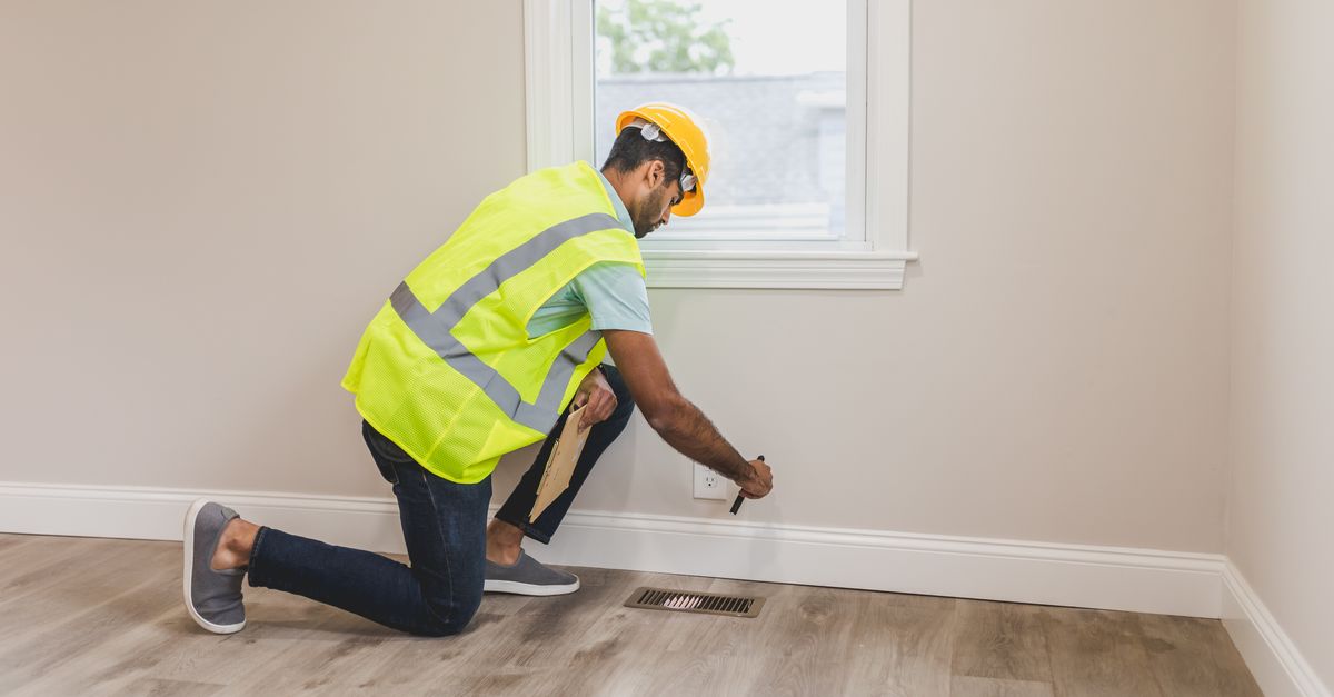 A homeowner inspecting insulation and framing in an unfinished attic space.