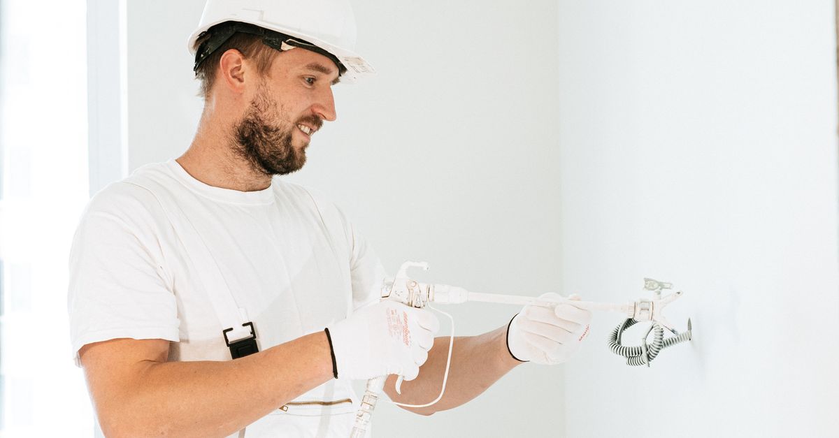 An electrician working on a ceiling bathroom exhaust fan installation.