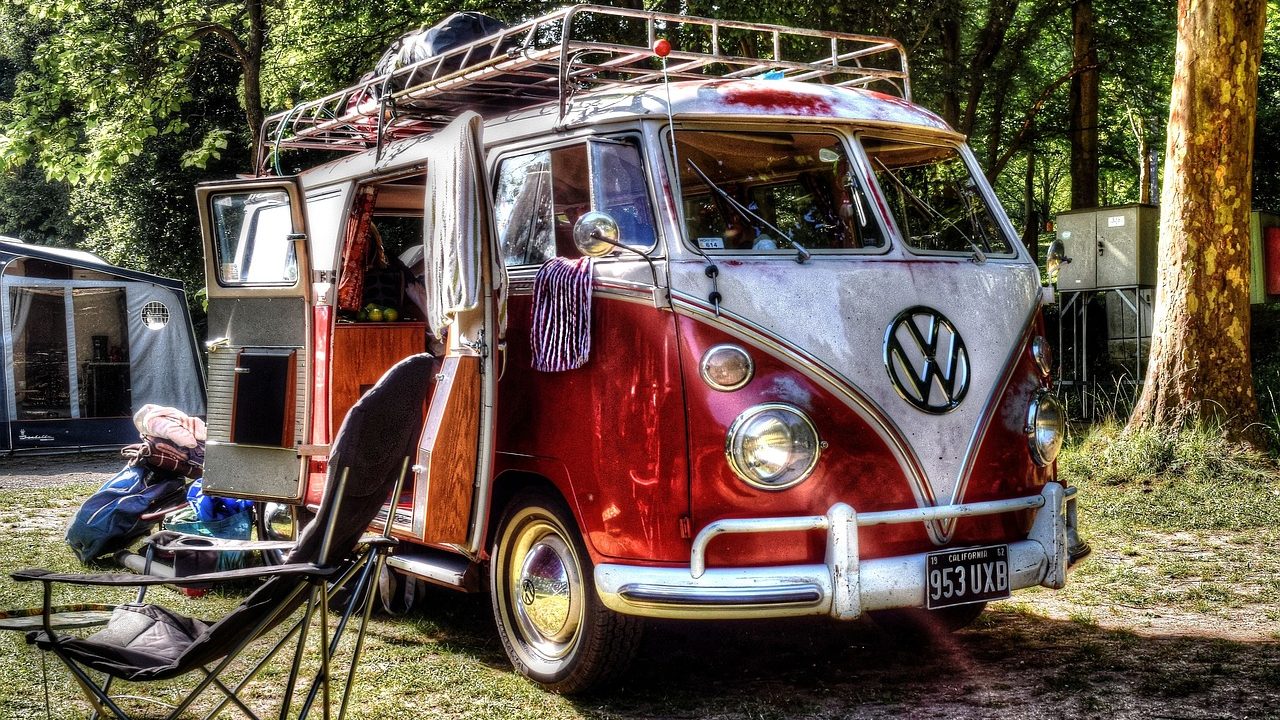 A popup camper fully set up at a scenic green campsite with its canvas sides and roof extended.
