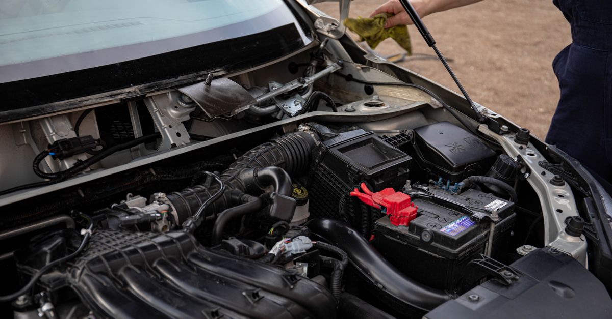 A mechanic inspecting the engine compartment of a side-by-side vehicle.