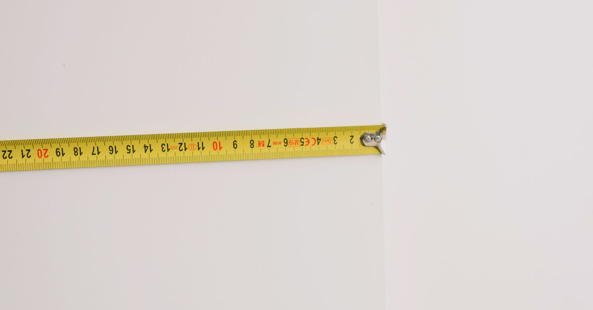 Contractor measuring residential carpeted flooring to calculate square footage for a cleaning estimate.