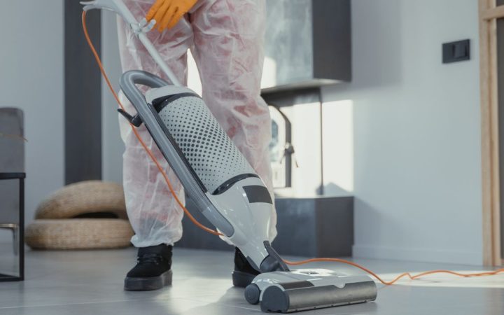 Homeowner removing and cleaning a central vacuum canister filter in a utility room.