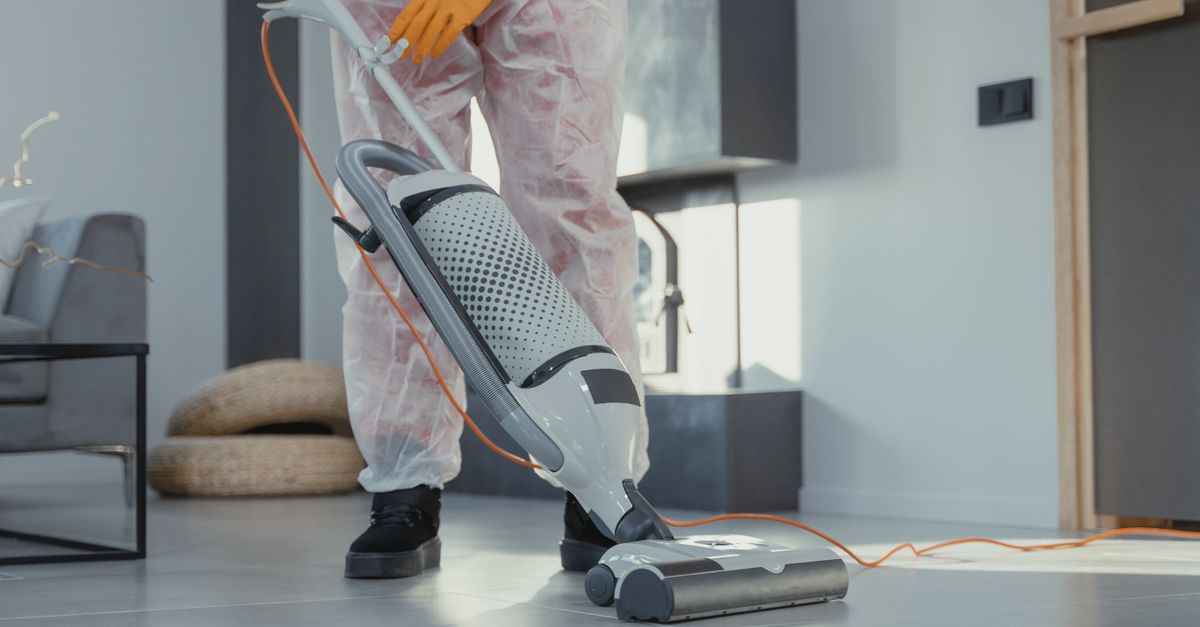 Homeowner removing and cleaning a central vacuum canister filter in a utility room.