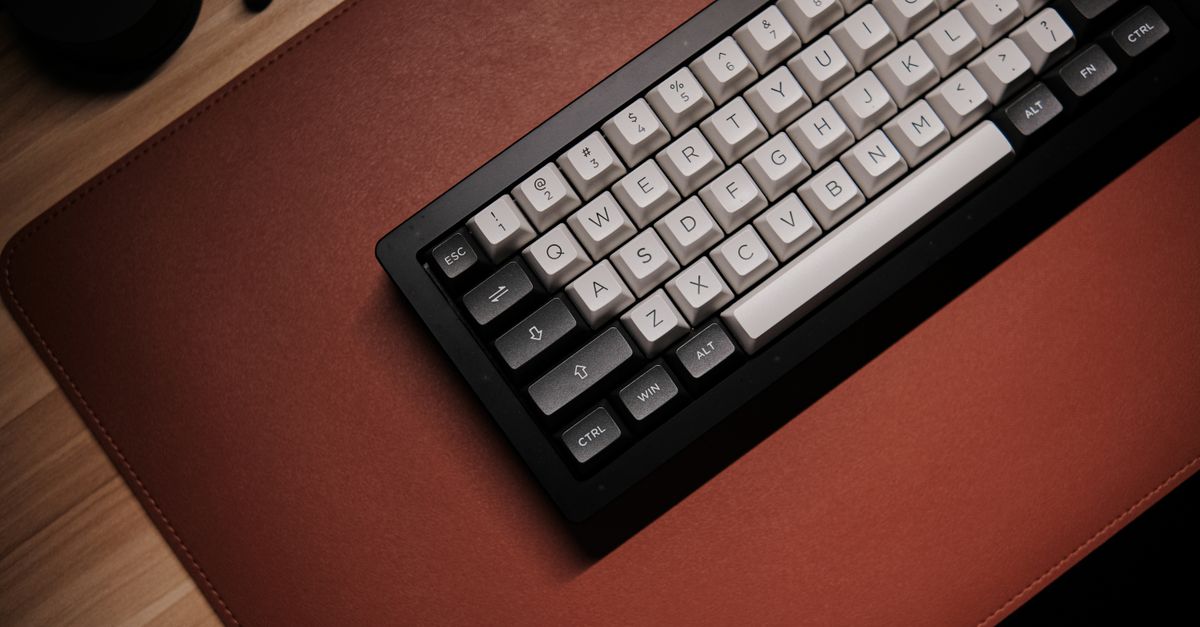 Close-up of hands typing on a mechanical keyboard resting on a dark wool felt desk pad.