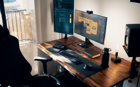 A clean wooden monitor shelf riser placed on a modern desktop holding a computer screen.