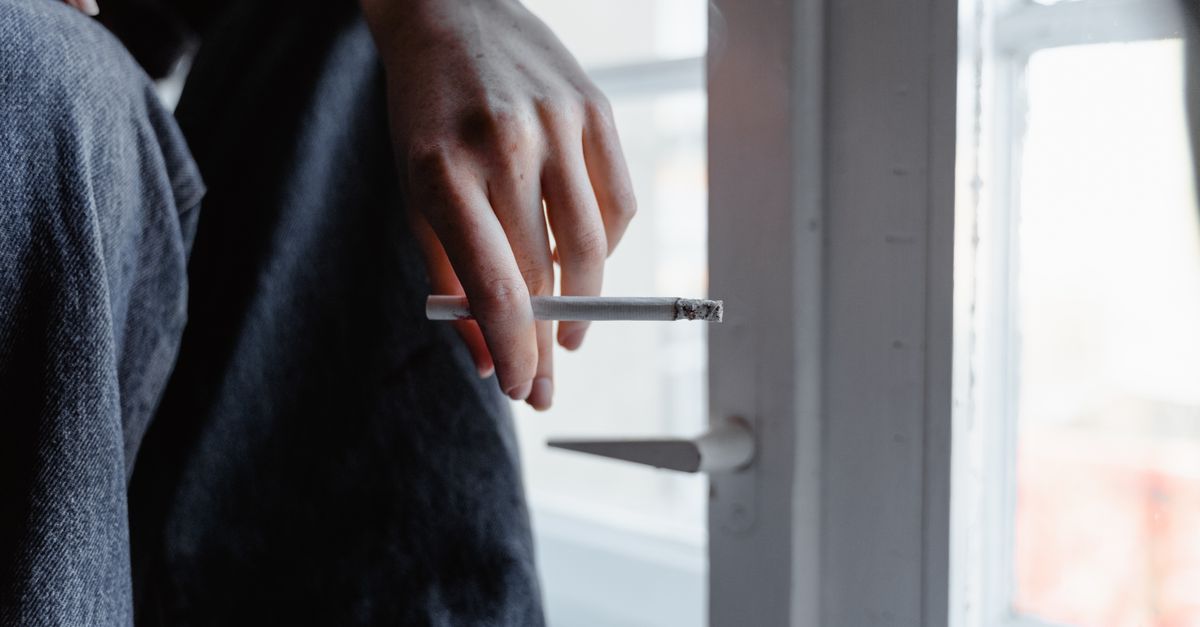 Homeowner performing an air leak test with a smoke pencil near a window frame.