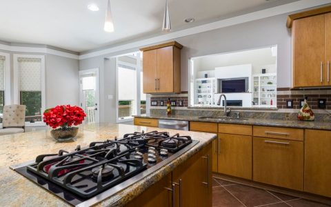 Sleek modern kitchen island featuring a glass cooktop and stainless steel appliances.