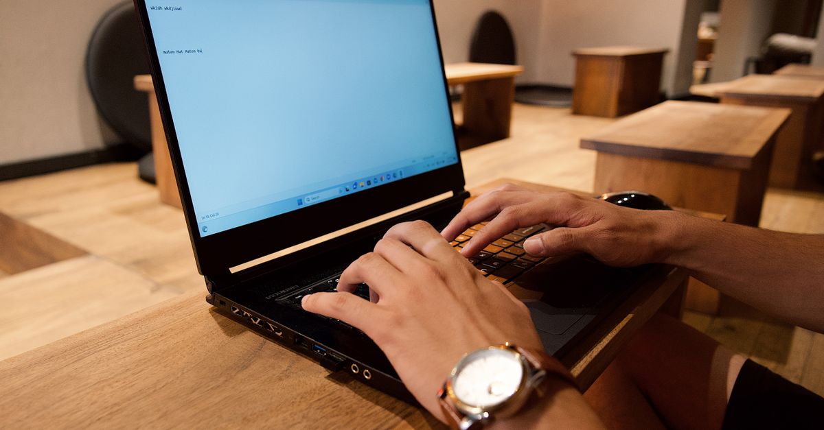 Remote worker typing on a laptop connected via an ethernet cable.