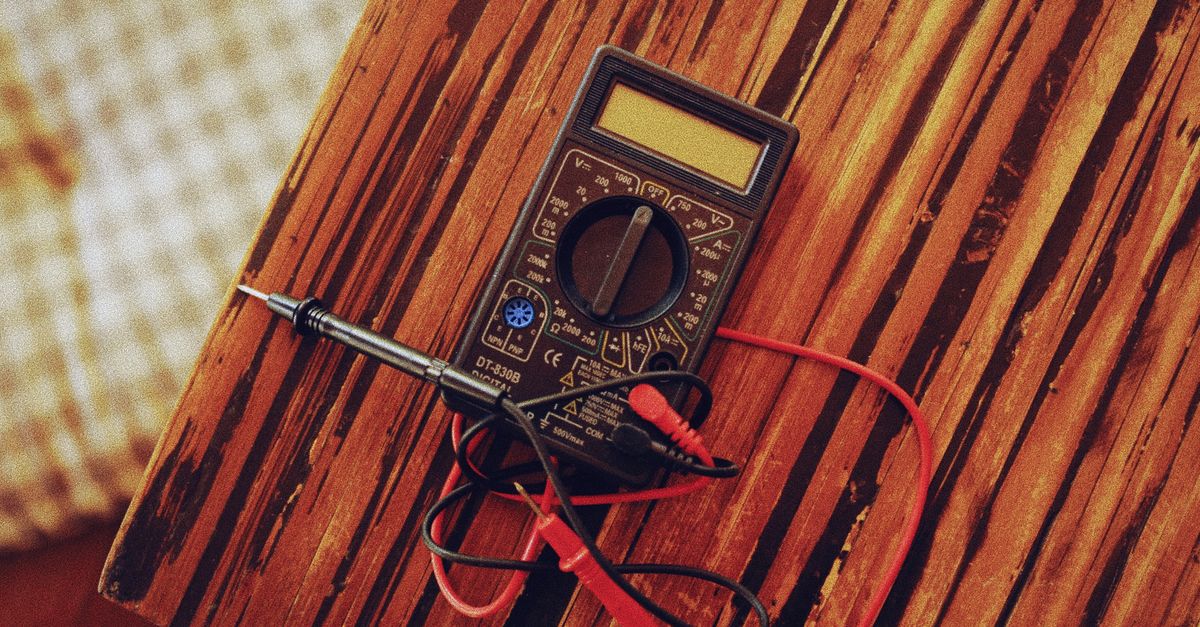 Close-up of hands using a digital multimeter for electrical testing