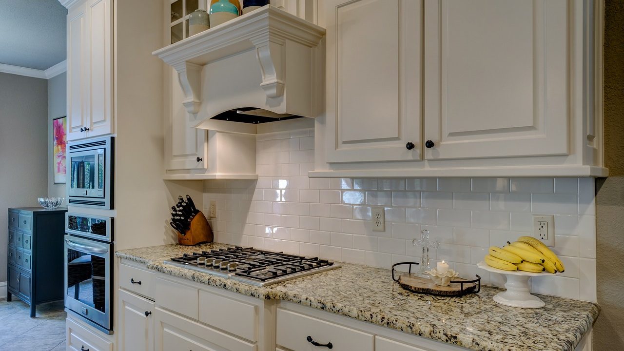 Stainless steel professional range hood installed above a modern gas cooktop in a renovated kitchen.