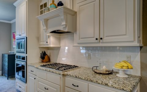 Stainless steel professional range hood installed above a modern gas cooktop in a renovated kitchen.