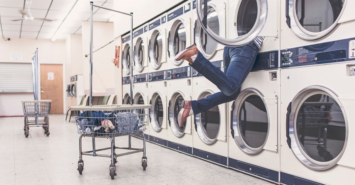 Homeowner loading wet clothes into a front-load laundry dryer