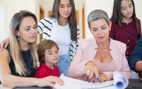 Parent and high school student sitting at a kitchen table reviewing course catalog and schedule together