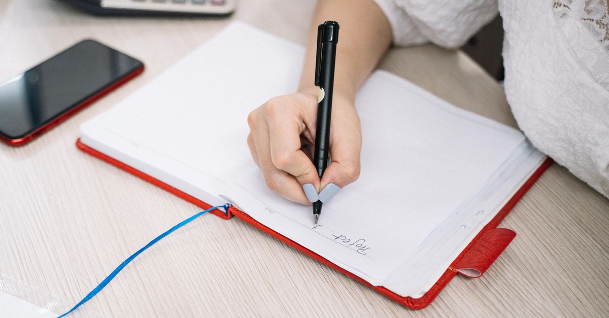 Person organizing graduation announcement address list in a notebook