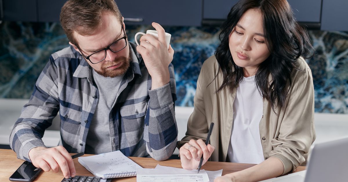 Family members reviewing a household sports expense spreadsheet at a kitchen table.