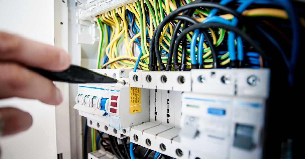 An electrician examining a home electrical panel during an inspection.