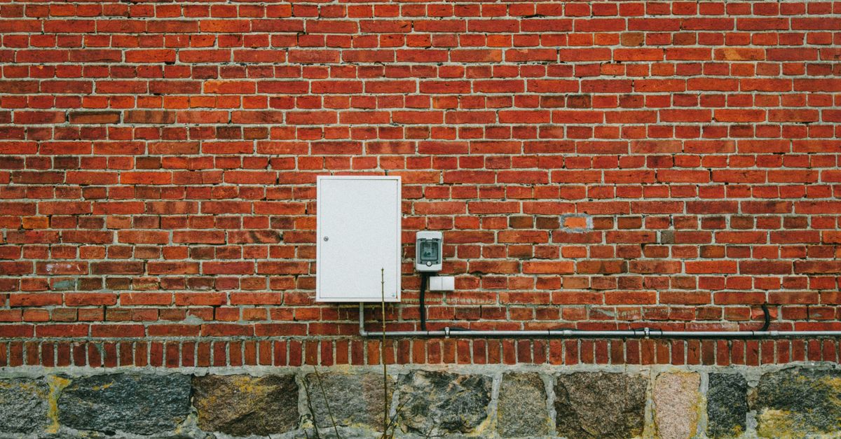 An exterior electric meter mounted on a residential brick wall.
