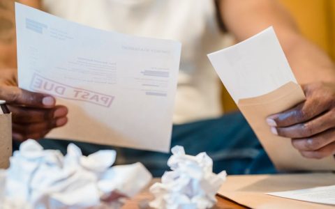 A person reviewing a utility bill and energy statement at a wooden desk.
