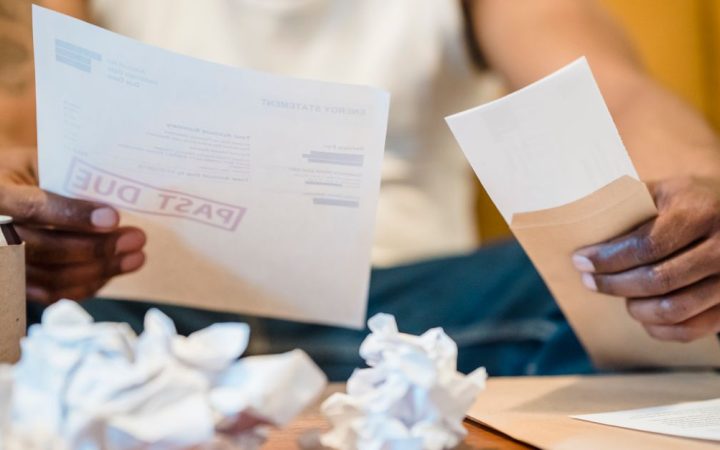 A person reviewing a utility bill and energy statement at a wooden desk.